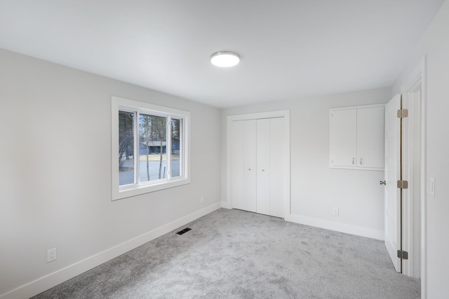 unfurnished bedroom featuring a closet, baseboards, visible vents, and carpet floors