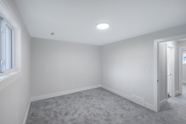 empty room featuring visible vents, baseboards, and carpet