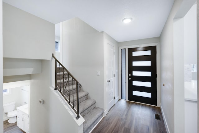 entrance foyer with visible vents, stairs, baseboards, and wood finished floors