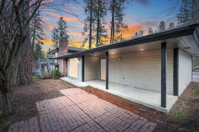 exterior space featuring stairs, a chimney, and a patio area