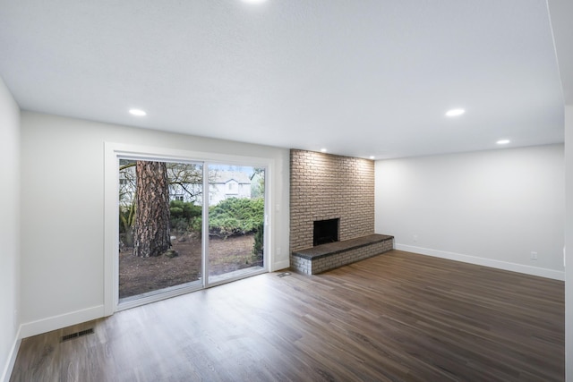 unfurnished living room featuring visible vents, baseboards, recessed lighting, a fireplace, and dark wood-style flooring