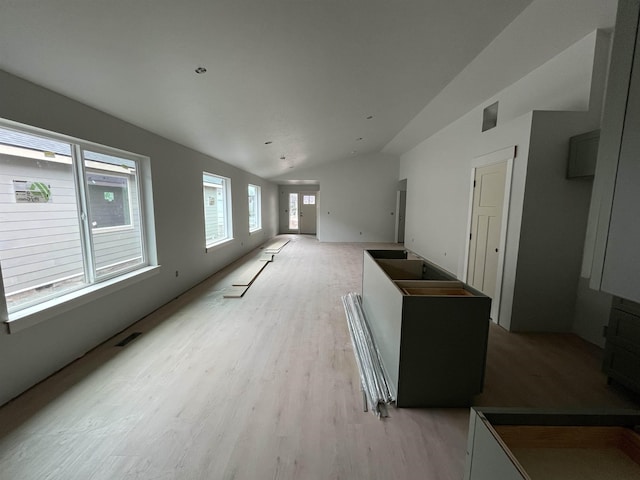 unfurnished living room featuring visible vents, light wood-type flooring, and vaulted ceiling