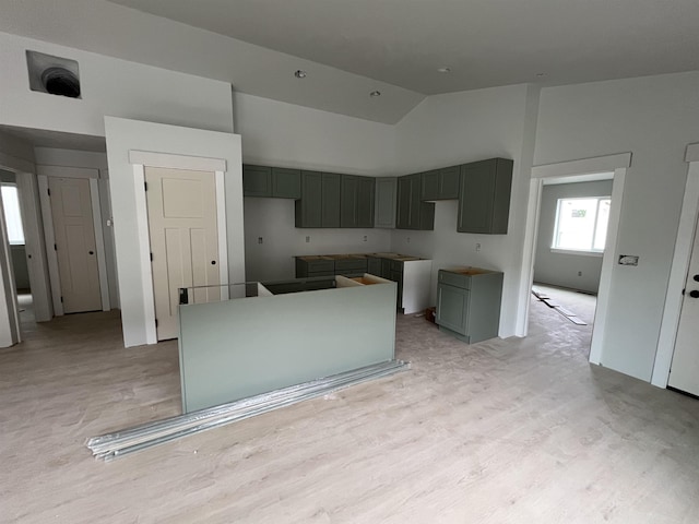 kitchen featuring light wood finished floors, high vaulted ceiling, gray cabinetry, and a kitchen island