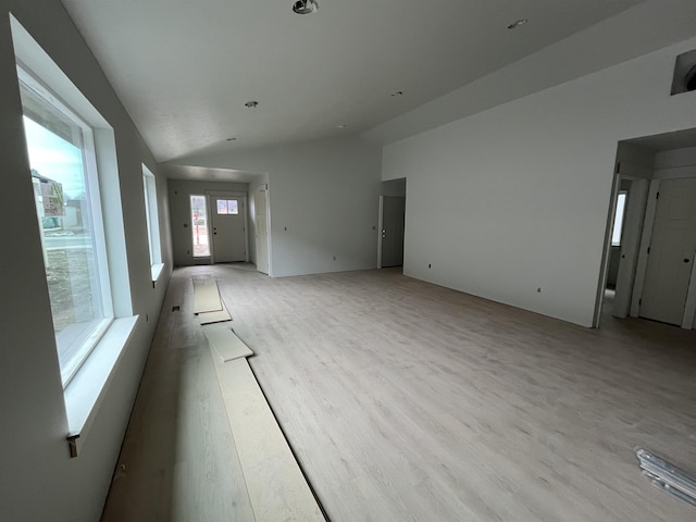 unfurnished living room featuring vaulted ceiling and light wood-style floors