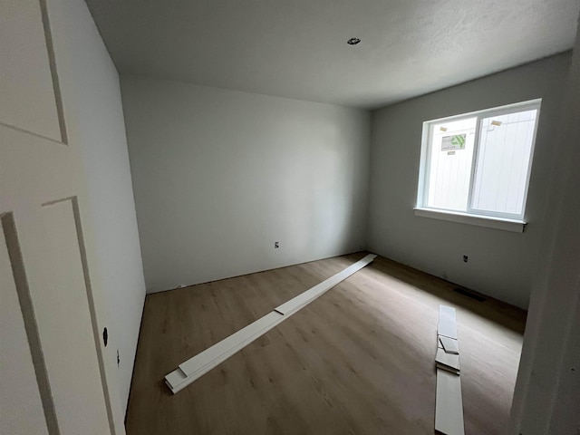 unfurnished room featuring wood finished floors and visible vents