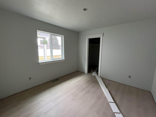 unfurnished bedroom featuring light wood-style floors, visible vents, and a closet