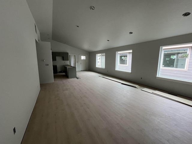 unfurnished living room featuring a healthy amount of sunlight, light wood-type flooring, and lofted ceiling