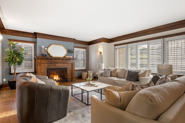 living area featuring a healthy amount of sunlight, a tile fireplace, crown molding, and baseboards