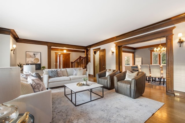 living room featuring stairway, an inviting chandelier, wood finished floors, and crown molding