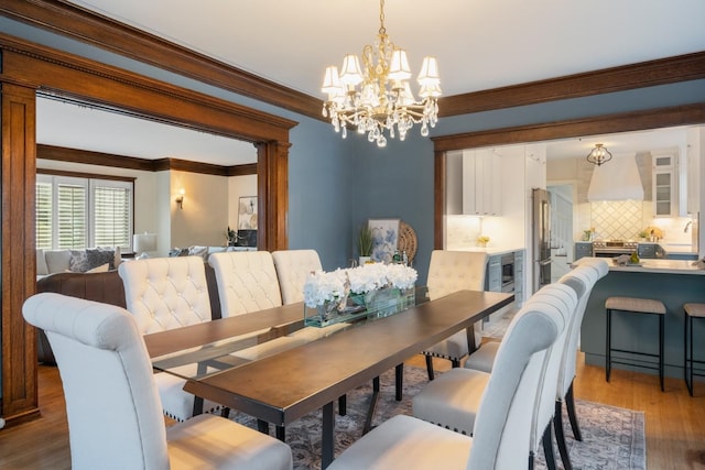 dining room featuring wood finished floors, a chandelier, and ornamental molding