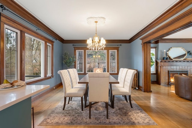 dining space with a notable chandelier, ornamental molding, and wood finished floors