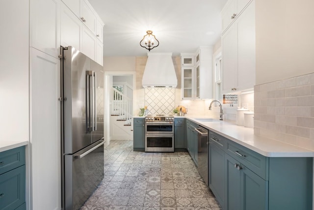 kitchen featuring backsplash, light countertops, appliances with stainless steel finishes, custom exhaust hood, and a sink