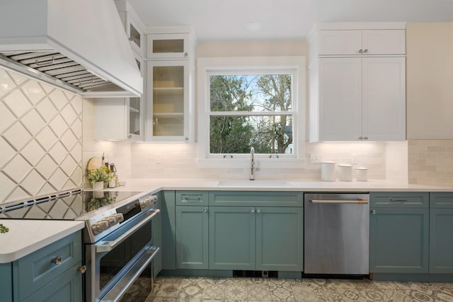 kitchen with custom exhaust hood, a sink, white cabinets, appliances with stainless steel finishes, and green cabinets