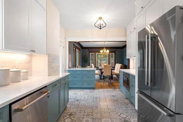 kitchen with blue cabinetry, light countertops, appliances with stainless steel finishes, a notable chandelier, and tasteful backsplash