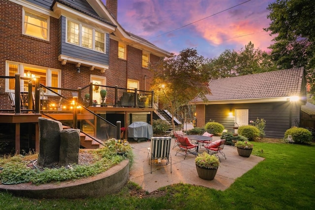 back of house at dusk with brick siding, stairs, a deck, a yard, and a patio area