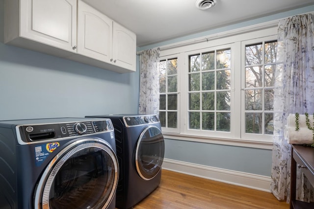 laundry room featuring visible vents, wood finished floors, cabinet space, baseboards, and washing machine and clothes dryer