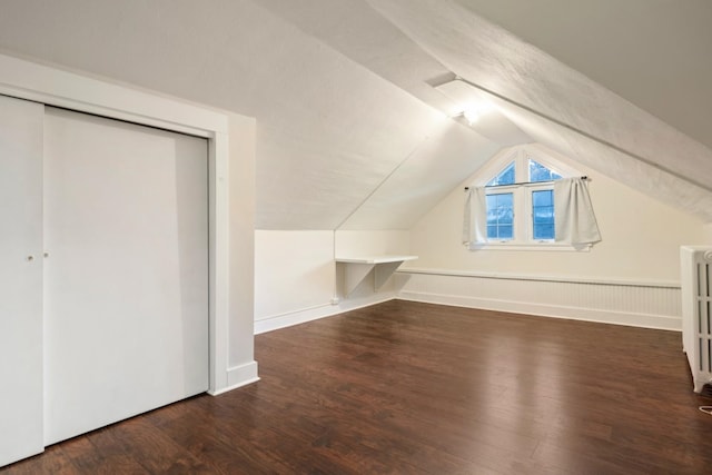 additional living space with vaulted ceiling, radiator, and wood finished floors