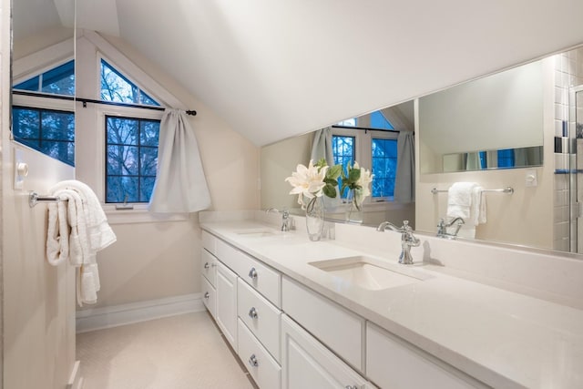 full bath featuring double vanity, lofted ceiling, and a sink