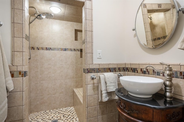 bathroom featuring a tile shower, a wainscoted wall, and vanity