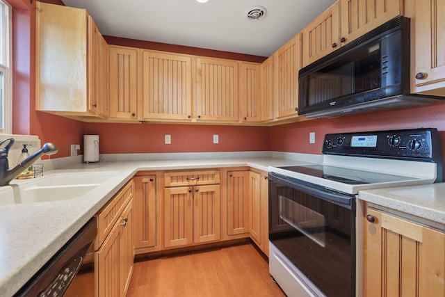 kitchen featuring visible vents, light wood finished floors, a sink, black appliances, and light countertops