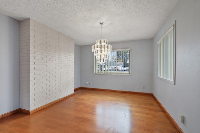 unfurnished room featuring a chandelier, baseboards, and wood finished floors