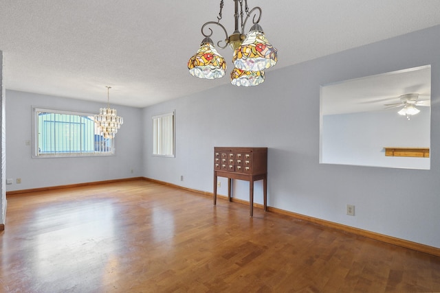 spare room with baseboards, a textured ceiling, wood finished floors, and ceiling fan with notable chandelier