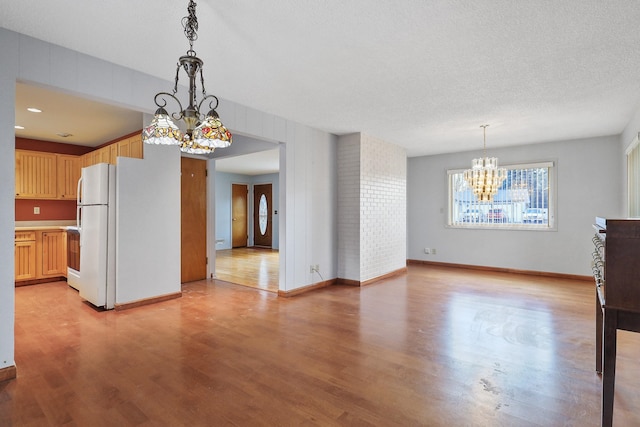 kitchen featuring decorative light fixtures, light countertops, freestanding refrigerator, light wood-style floors, and a notable chandelier