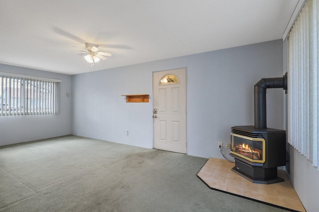 living room with carpet, ceiling fan, and a wood stove