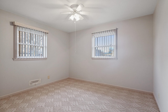 carpeted empty room with visible vents, baseboards, and a ceiling fan