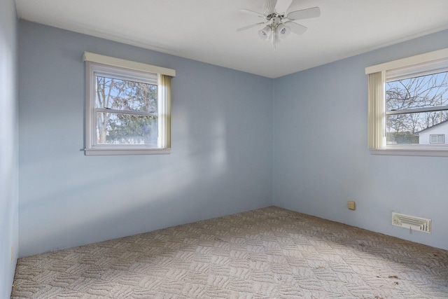 spare room with a ceiling fan, visible vents, a wealth of natural light, and carpet floors