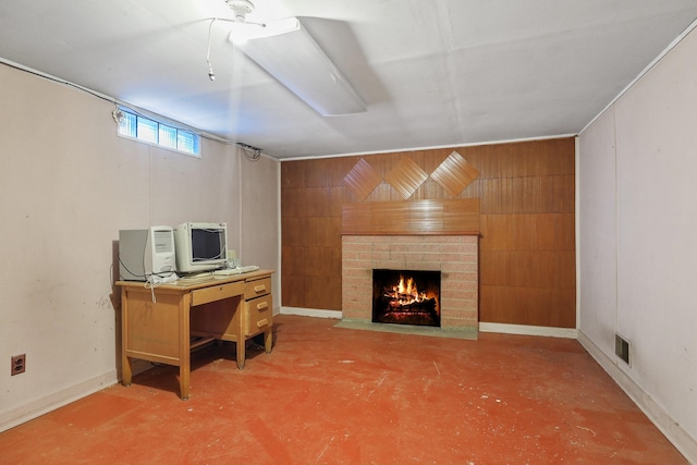 interior space with visible vents, concrete floors, wood walls, baseboards, and a brick fireplace