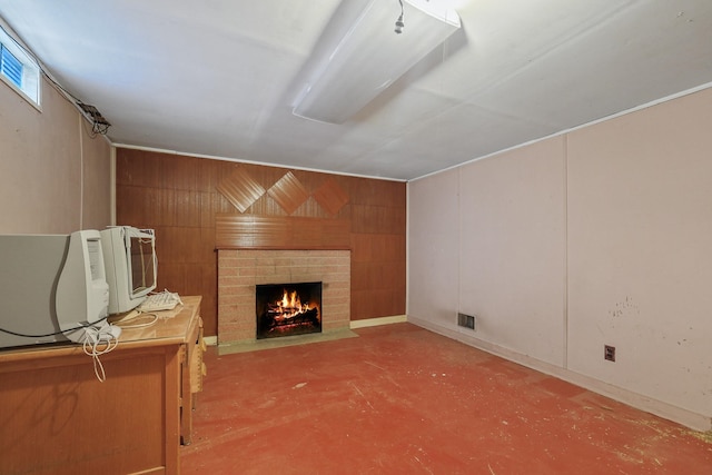 living room featuring a brick fireplace, wooden walls, finished concrete flooring, and visible vents