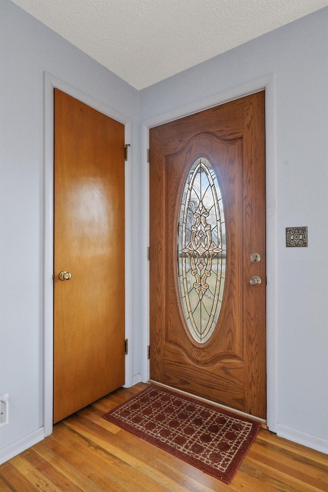 entrance foyer with baseboards, a textured ceiling, and wood finished floors