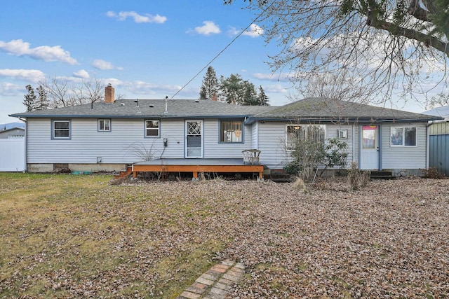 rear view of house with a deck, a yard, fence, and a chimney