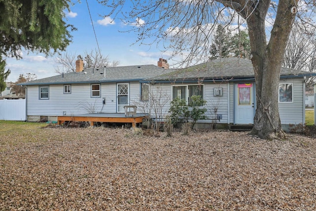 back of property featuring a deck, fence, and a shingled roof