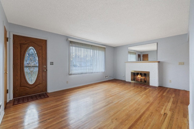 entryway featuring a textured ceiling, light wood-style flooring, and a fireplace