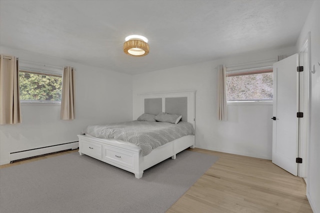 bedroom featuring light wood-type flooring and baseboard heating