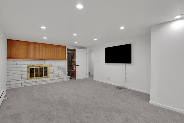 unfurnished living room with a stone fireplace, carpet flooring, recessed lighting, and baseboards