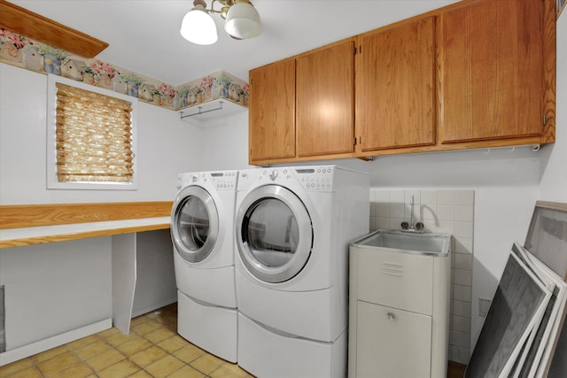 laundry room with cabinet space, light tile patterned floors, washing machine and dryer, and a sink