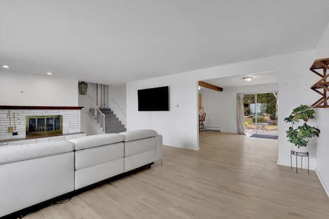 living area with baseboard heating, recessed lighting, a fireplace, and light wood finished floors