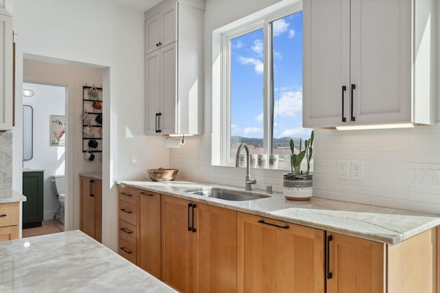 kitchen with tasteful backsplash, light stone counters, and a sink