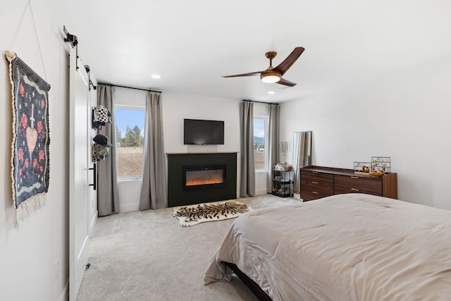 bedroom with a glass covered fireplace, multiple windows, carpet, and baseboards