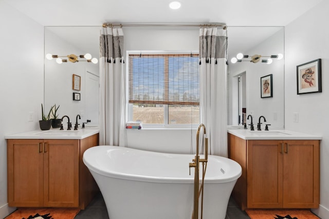 full bath with a freestanding bath, two vanities, and a sink