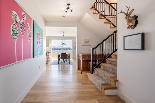 entrance foyer with stairs, baseboards, light wood-style floors, and an inviting chandelier