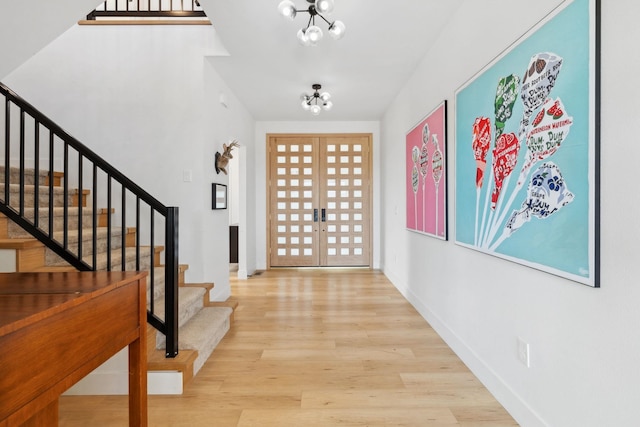 entryway featuring wood finished floors, french doors, baseboards, a chandelier, and stairs