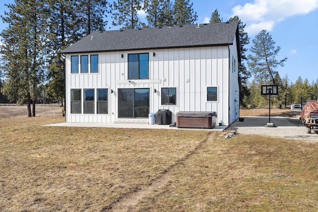 rear view of house featuring a patio area, a yard, board and batten siding, and a hot tub