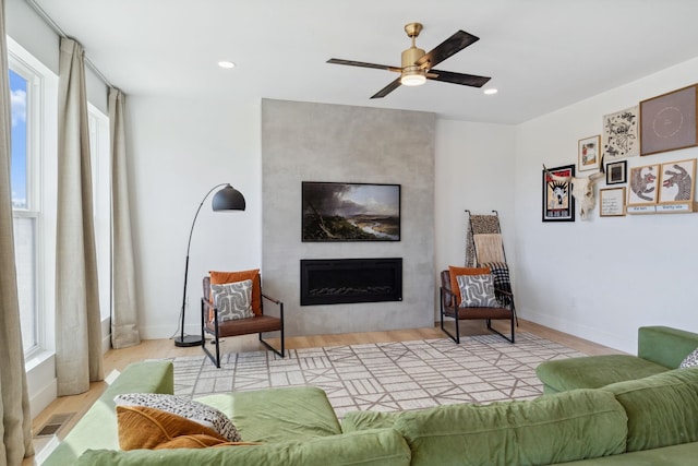 living area with recessed lighting, a large fireplace, and wood finished floors