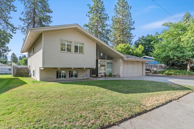 split level home featuring a garage, concrete driveway, a front lawn, and fence