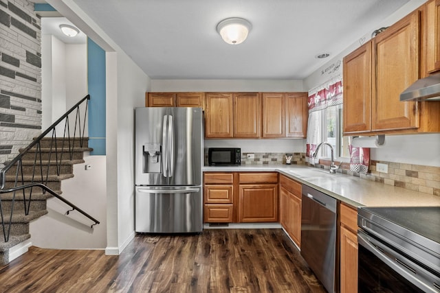 kitchen featuring dark wood finished floors, a sink, light countertops, appliances with stainless steel finishes, and brown cabinets