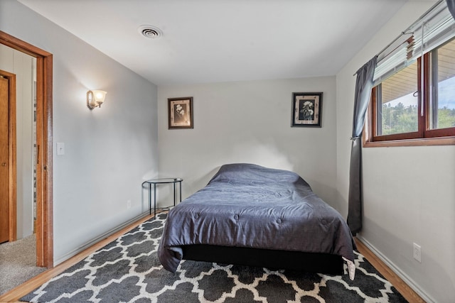 bedroom with visible vents, baseboards, and wood finished floors